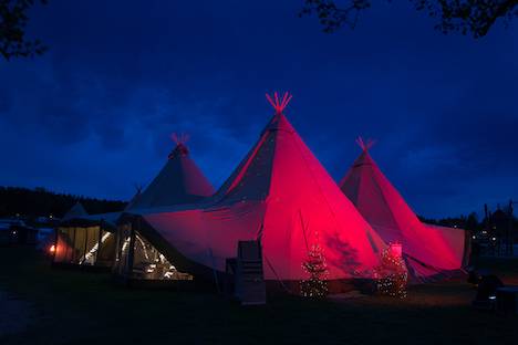A Tipi Tent hire for a party and lit up red at night.