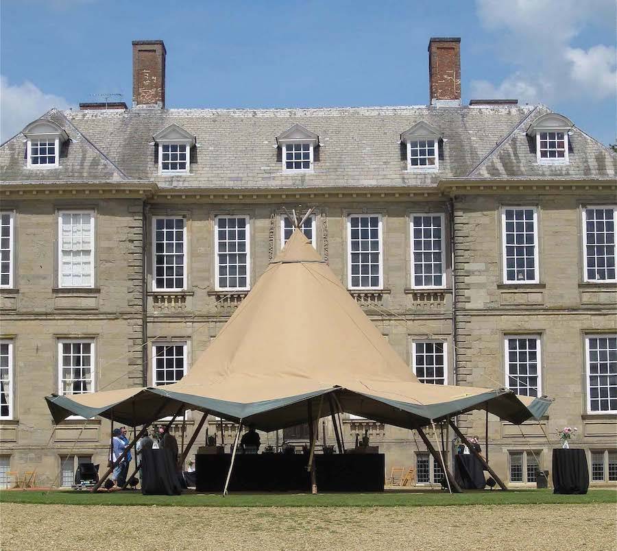 The Giant Tipi or Stratus 72 is positioned in front of a Stately home with its sides up or a hot summers day.