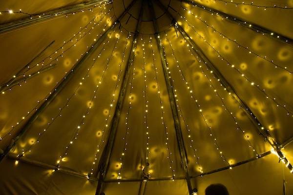 Tipi hire featuring a magical fairy light canopy, creating an enchanting ambiance for special events.