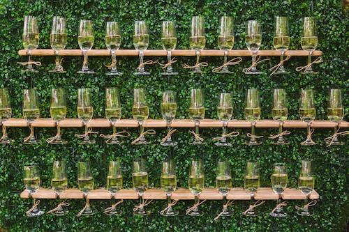 Prosecco Wall with a green moss background and wooden champagne flutes. For wedding and event hire.