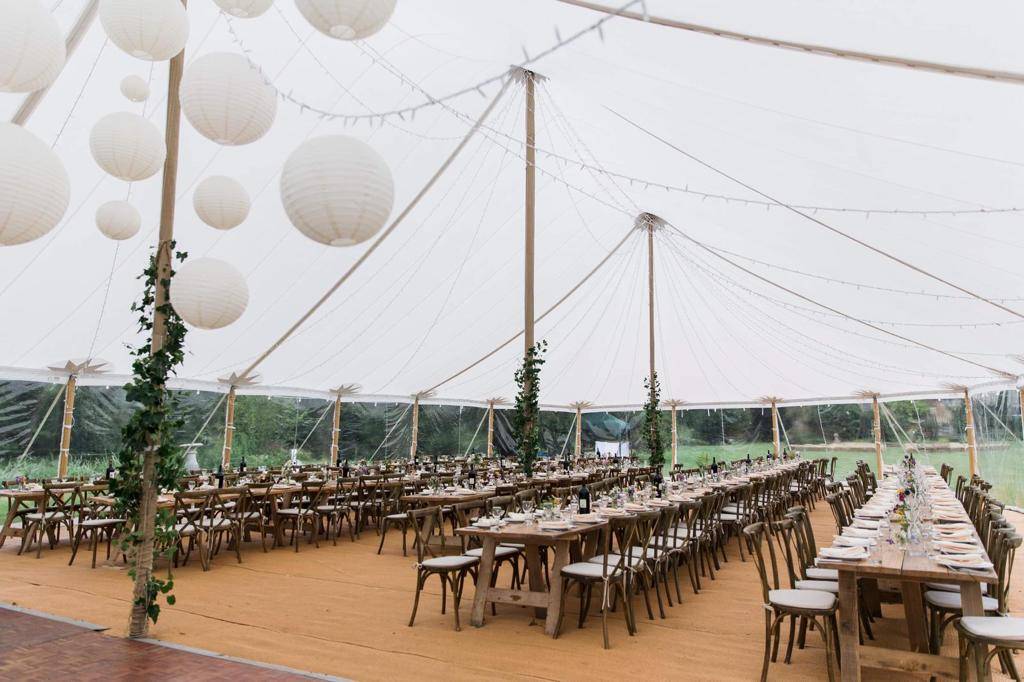 The bright interior of a Sperry Tent during the day with rustic wooden benches and chairs.