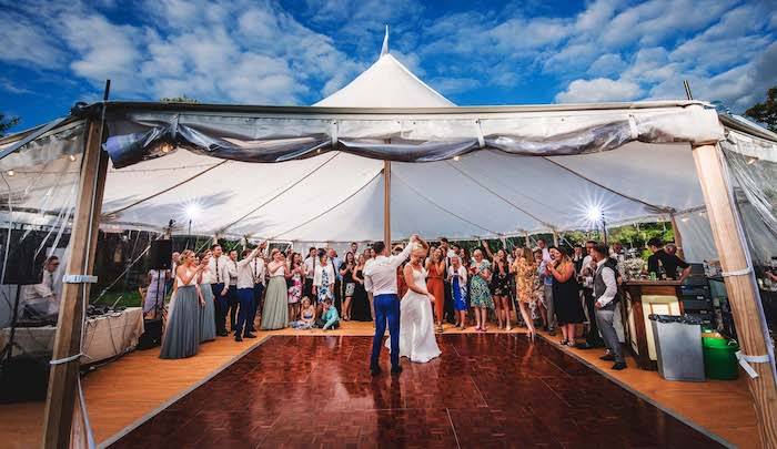 A wedding couple, on a wooden dancefloor for their first dance inside a Sperry Tent they've hired for their wedding.