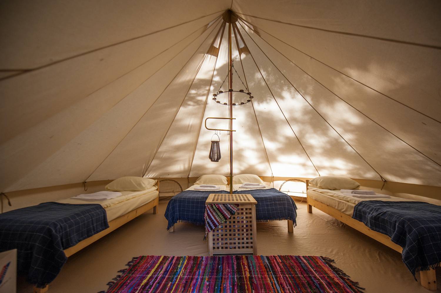 Bell Tent for a festival wedding with beds and multicoloured rug.