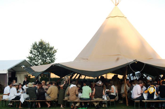 A lively tipi filled with festival-goers, radiating vibrant energy and excitement at a music festival.