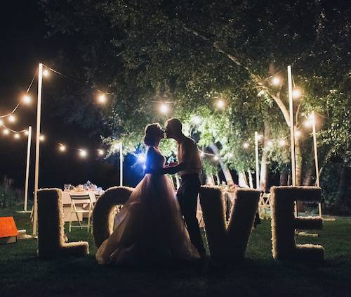 Romantic Newlyweds' Kiss Amidst Stylish Wedding Ceremony with Lamps